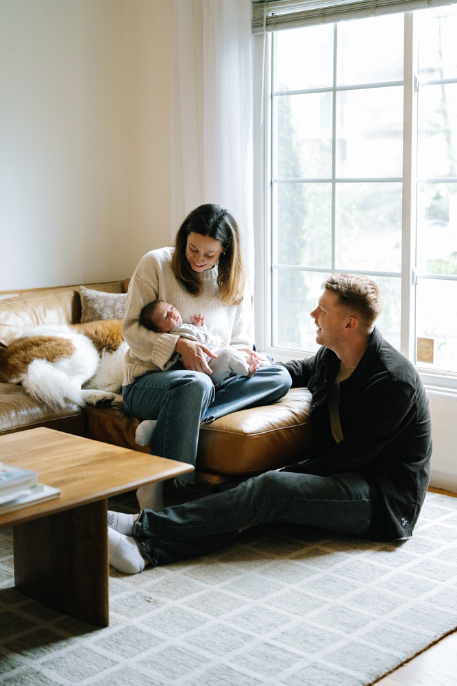 Parents sitting together on couch admiring their baby