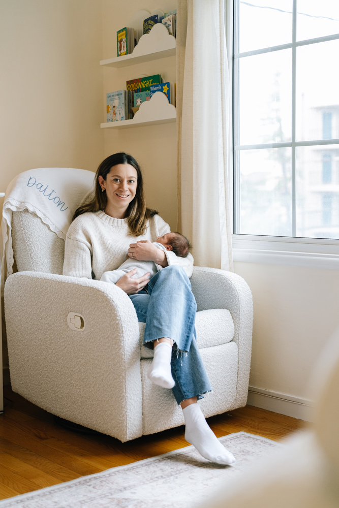 Mother sitting in armchair holding baby by window