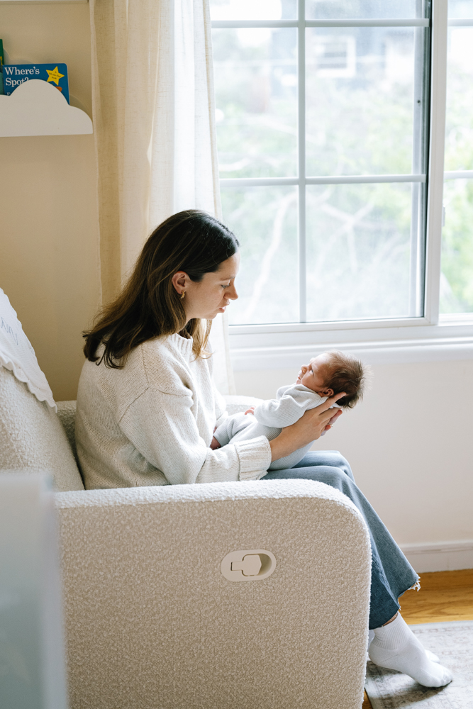 Mom soothing newborn in nursery with natural light