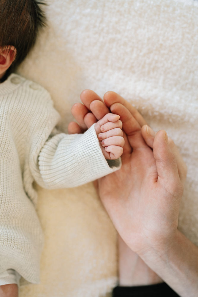 Close-up of baby holding parent’s finger