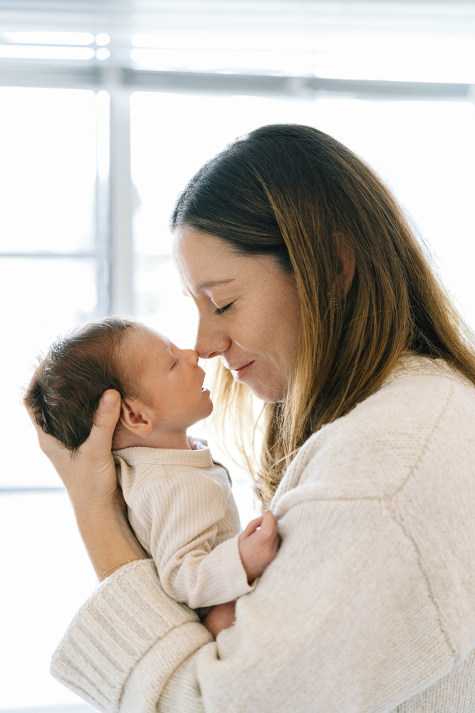 Mother holding baby close near window light
