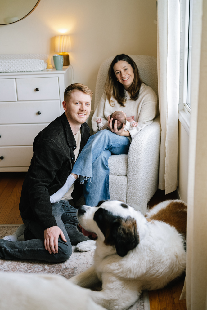 Parents sitting on nursery floor with baby and family dog
