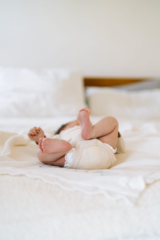 Close-up of baby’s tiny feet on white bedding