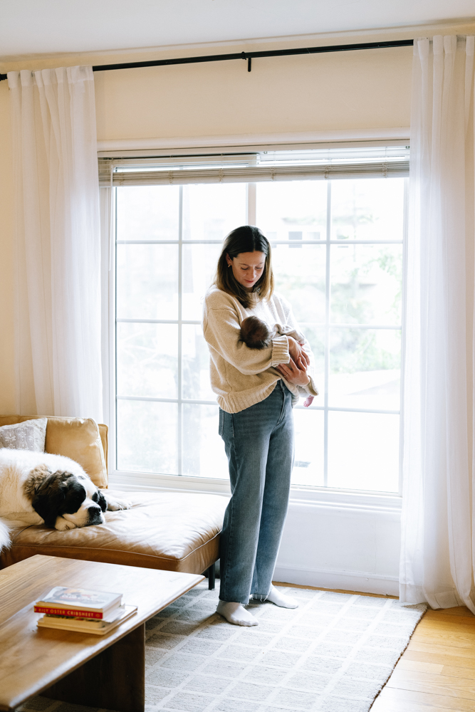 Mother holding newborn near window in natural light