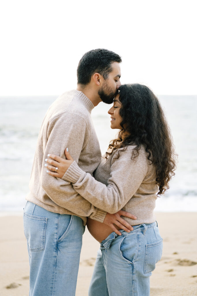 Intimate maternity portrait Half Moon Bay — partner kissing forehead while holding baby bump