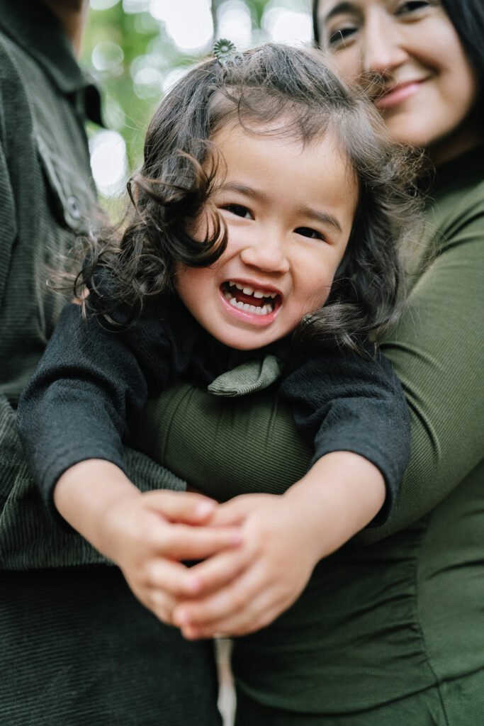 Candid family portrait Redwood Grove Nature Preserve — little girl laughing and hugging mom in redwood forest Bay Area