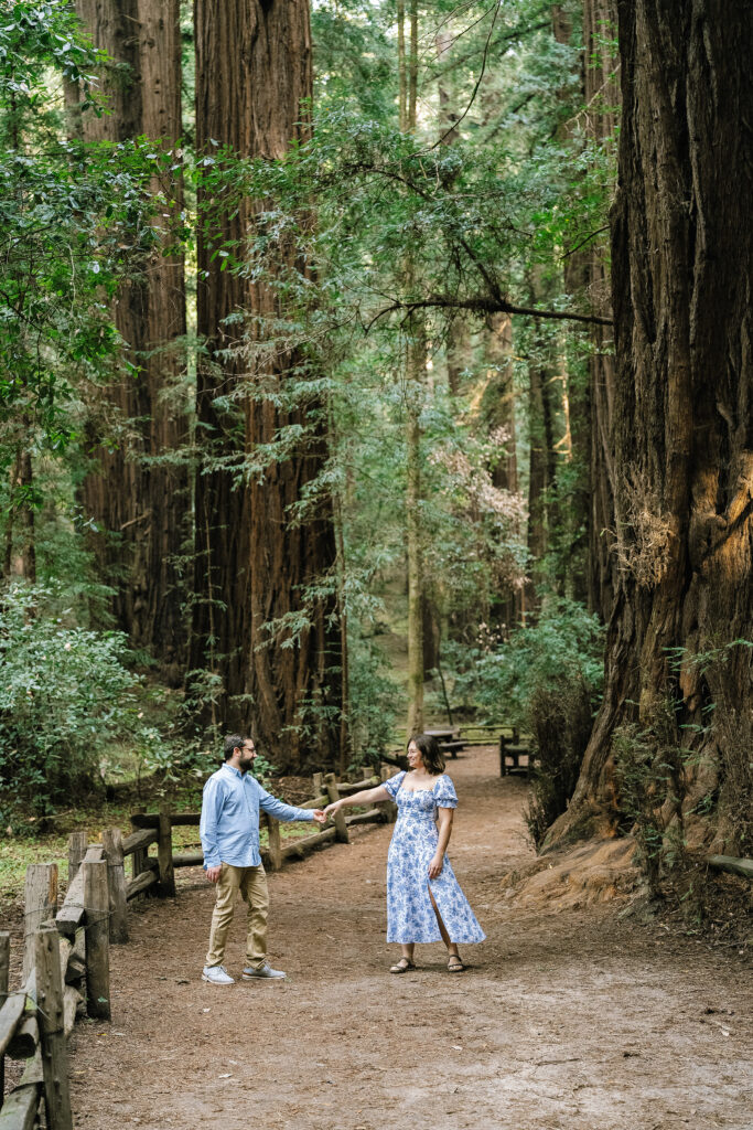 Lifestyle maternity session Santa Cruz forest — couple holding hands among ancient redwood trees